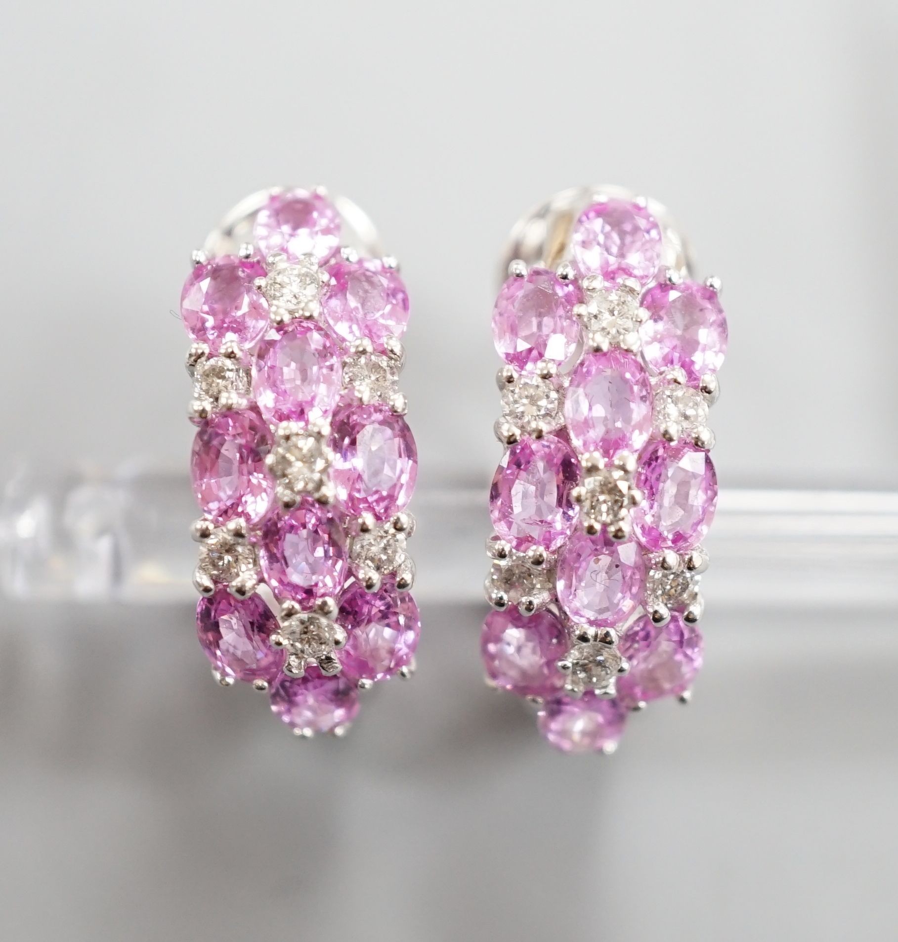A modern pair of 14k white metal, pink sapphire and diamond cluster set half hoop earrings, 17mm, gross weight 8.3 grams.